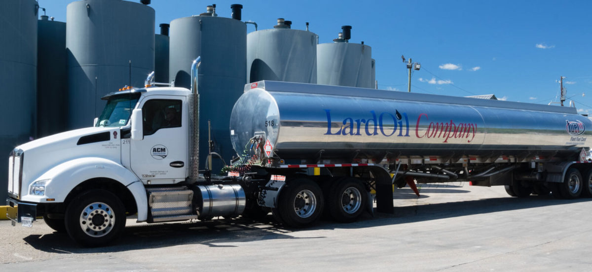 large lard oil truck parked outside large fuel containers